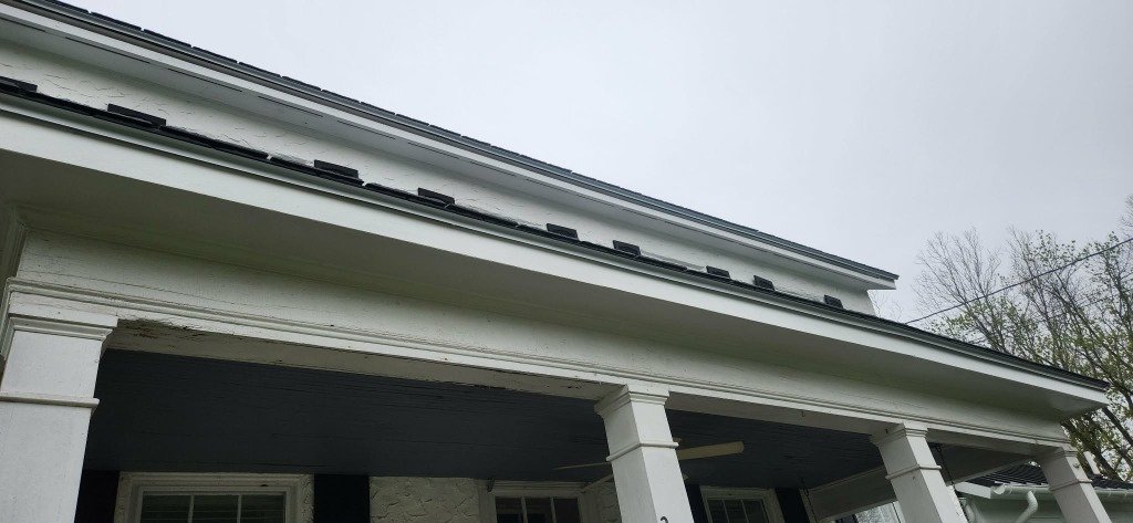 Technician installing gutter guards white stucco home